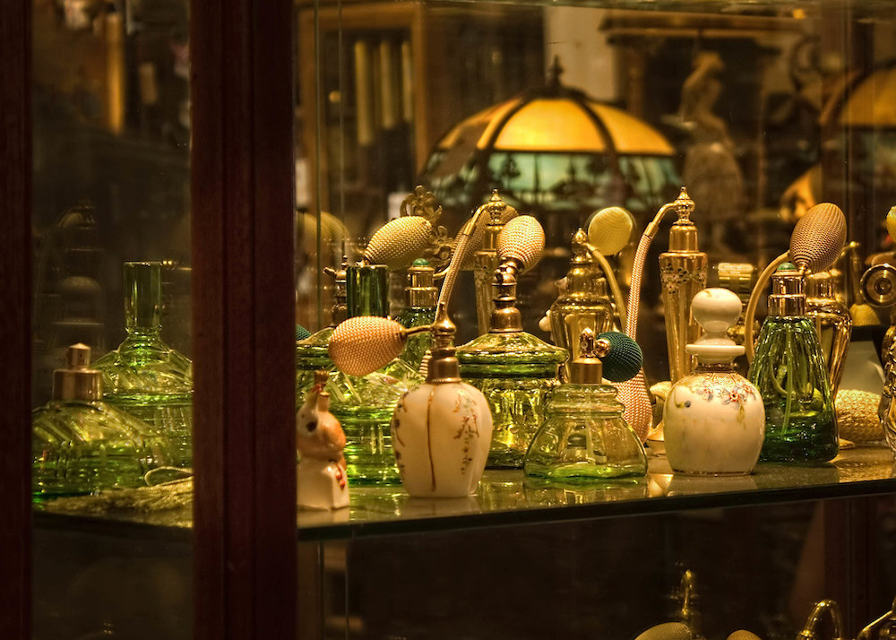Photo of antique perfume bottles and atomizers on the shelf of an antique store.