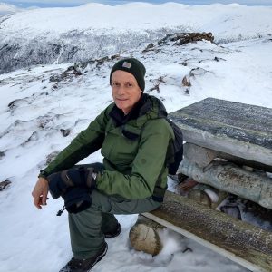 Christopher Preston seated on a bench in the snow.