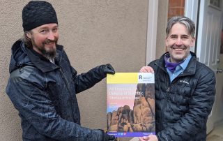 Craig Fox is presented with his thesis defence poster by Chris Smeenk