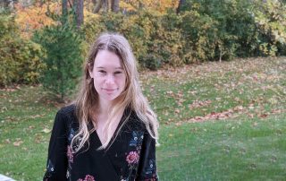 Photo of Emily Adlam in front of fall trees behind WIRB