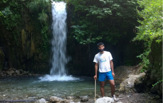 Farshid Soltani standing near the edge of a small pool beneath a water fall