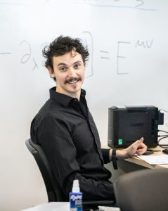 Jon Bowen seated in front of a whiteboard