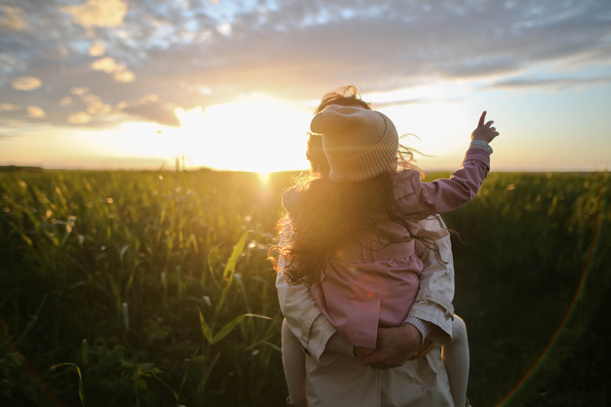 Mother and daughter in field at sunset